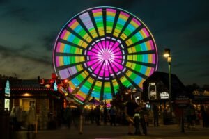 A vibrant Ferris wheel lights up the night sky at a theme park in Pigeon Forge, Tennessee.