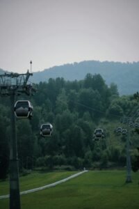 Cable cars moving over a green landscape with hills and trees, capturing outdoor travel and leisure.