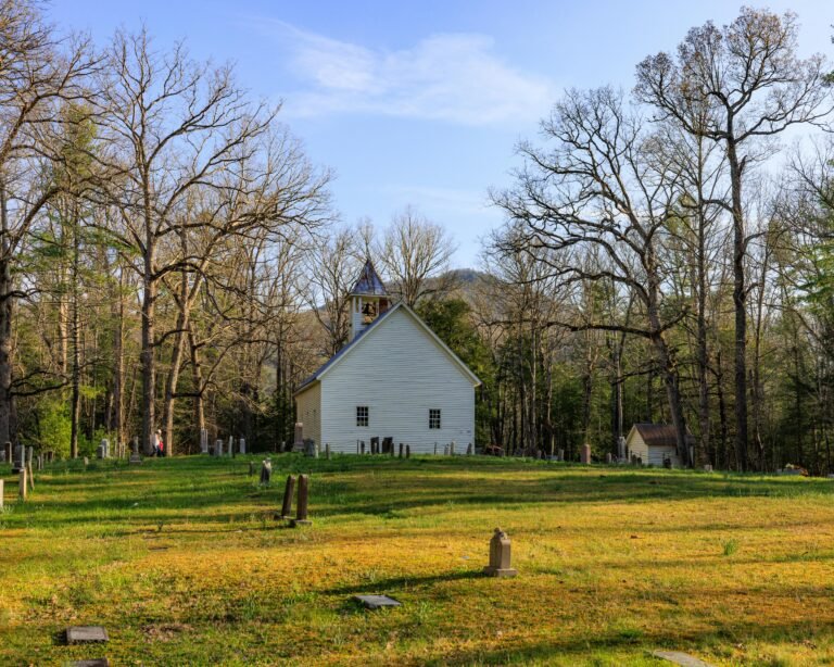 White church surrounded by a historic cemetery in Tennessee with scenic forest backdrop.