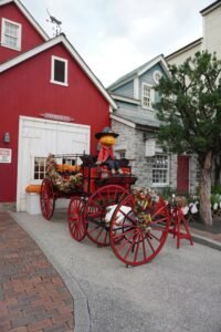 A festive Halloween setup with a pumpkin figure on a vintage cart in a picturesque Japanese village.