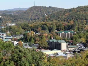 Aerial view of Gatlinburg, Tennessee showcasing green rooftops amid lush autumn foliage.